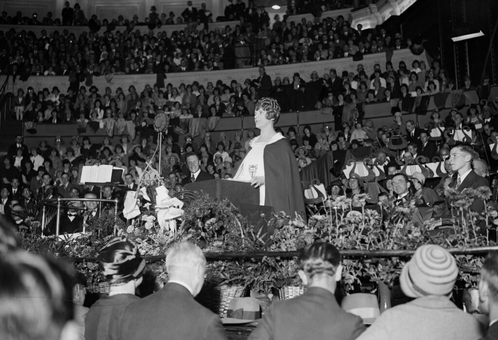 Preaching to a packed auditorium. Source: The Gospel Coalition